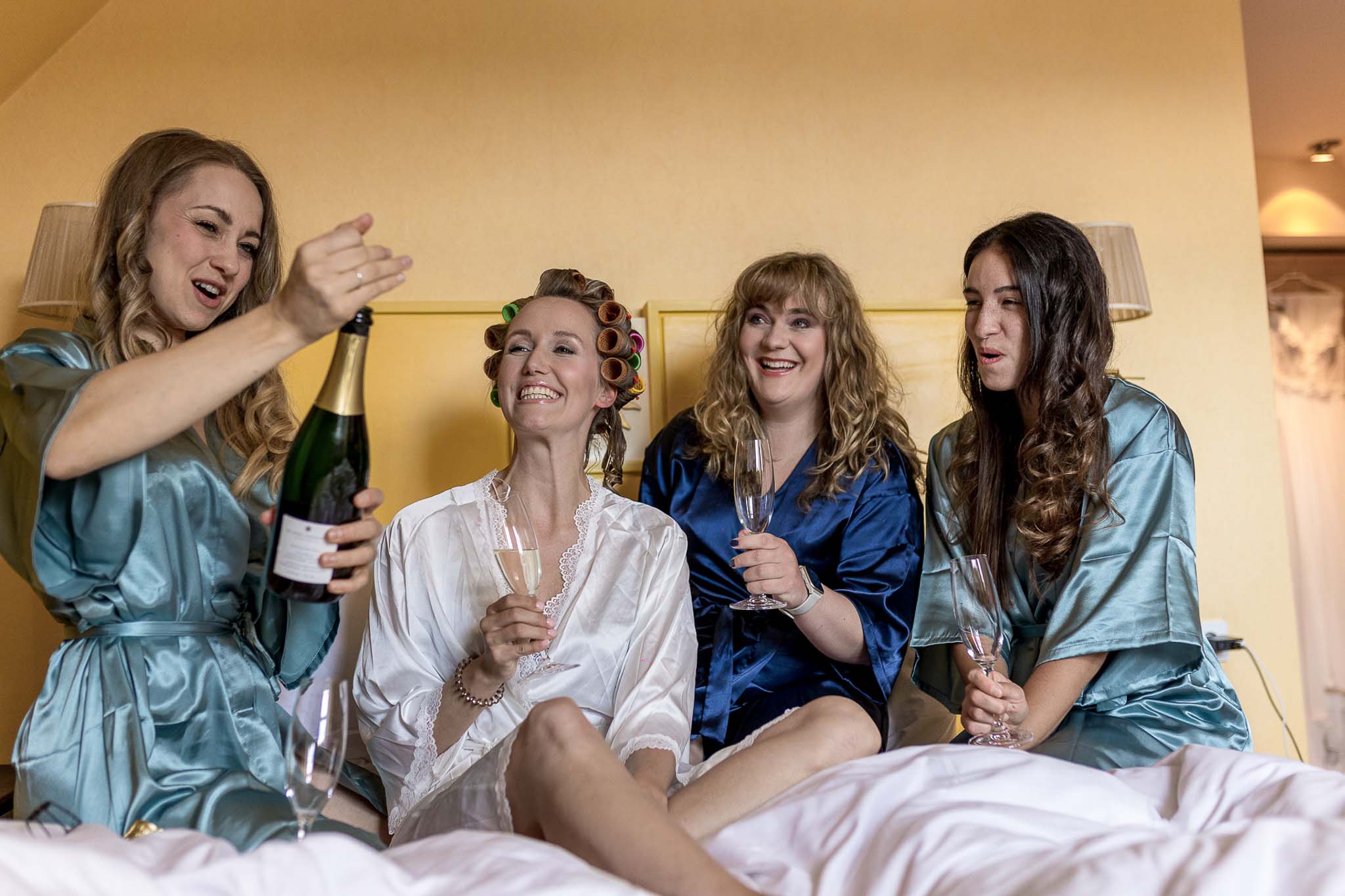 Getting ready mit Sekt Braut und Freundinnen stossen beim Getting ready auf dem Bett mit Sekt an