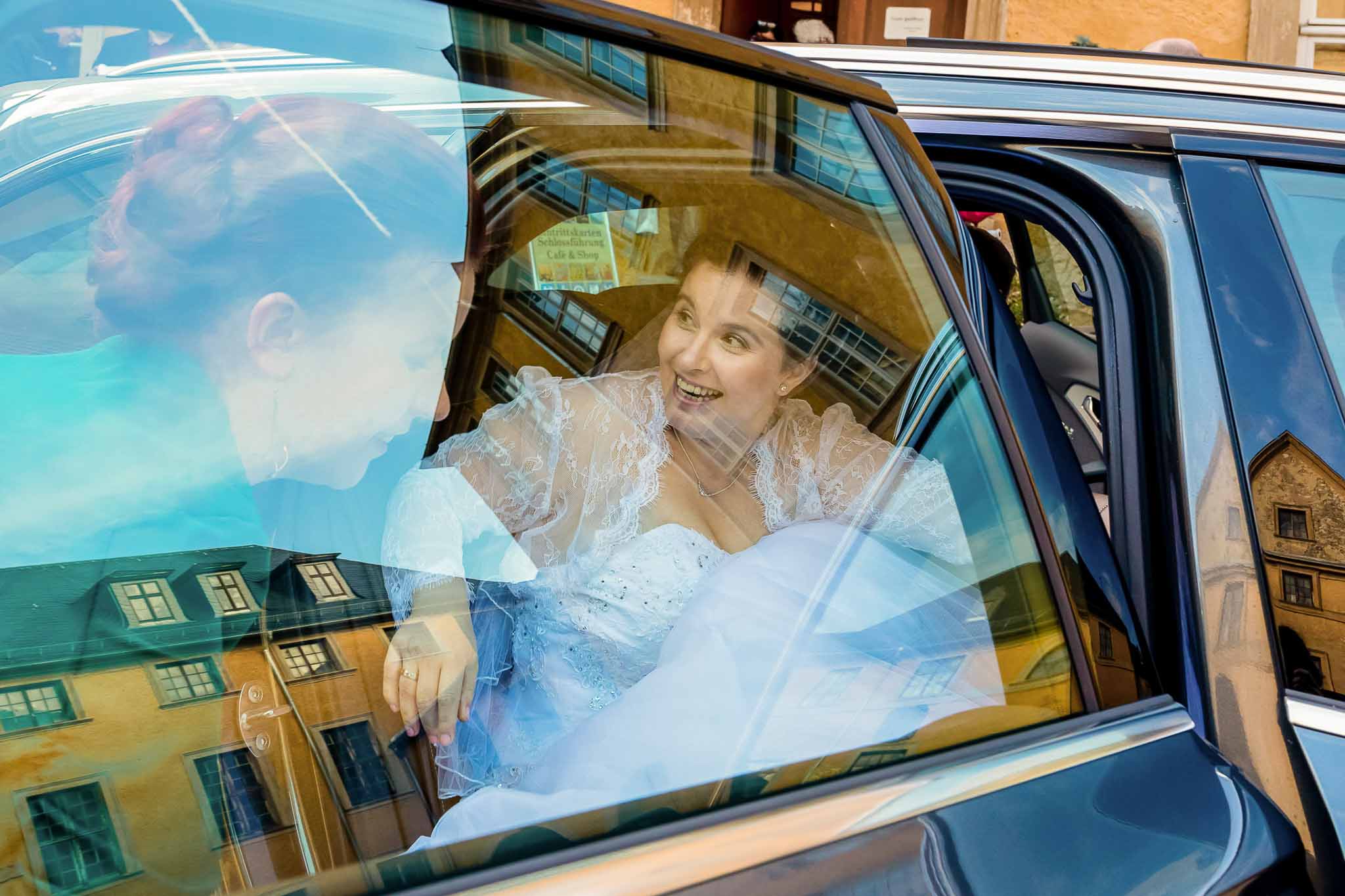 Brautpaar spiegelt sich im Seitenfenster des Hochzeitsautos
