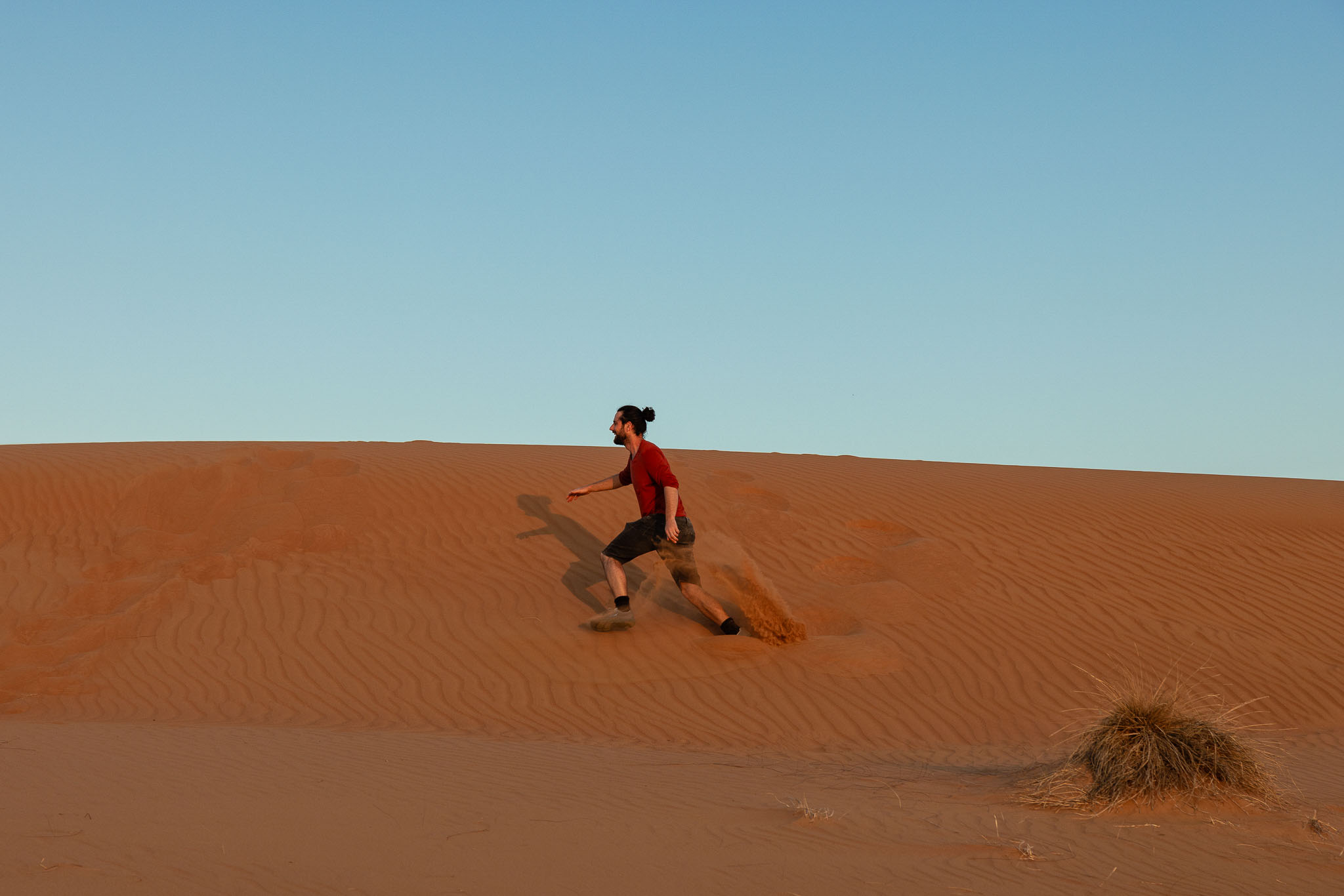 Kai Eisentraut springt über eine rote Sanddüne unter blauem Himmel