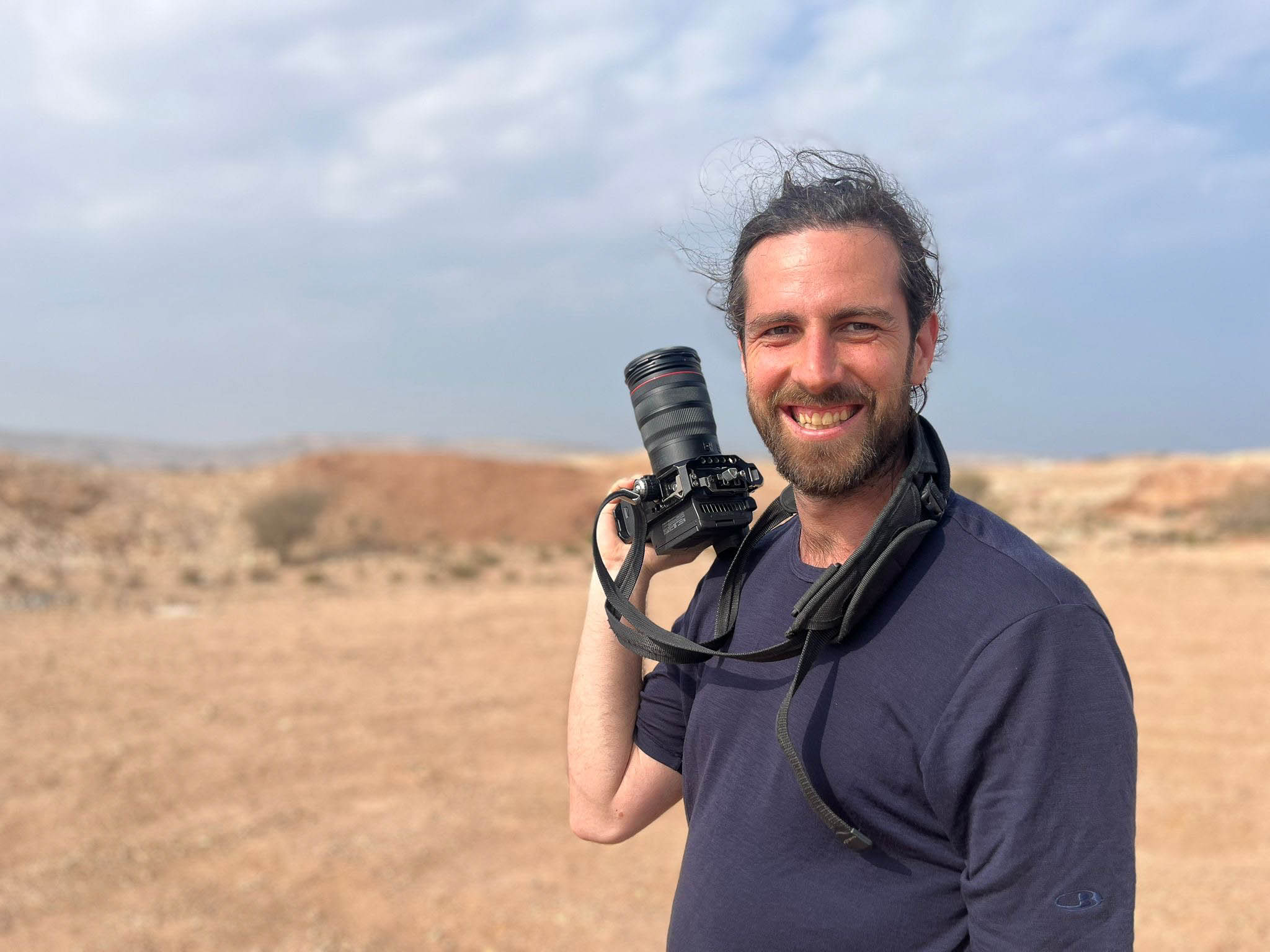 Hochzeitsfotograf Kai Eisentraut lacht mit seiner Kamera in einer Wüstenlandschaft